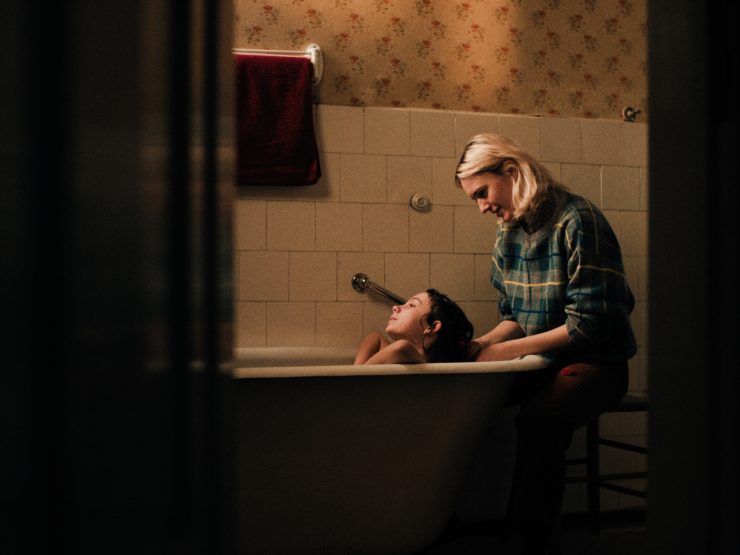 Eine Kind ist in einer Badewanne und eine Frau sitzt dahinter und wäscht die Haare des Kindes.