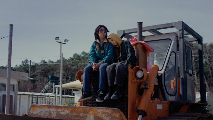 Filmstill aus 'Paternal Leave': Zwei Jugendliche sitzen aneinder angelehnt auf einem Bagger.