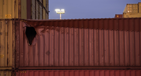 Ein roter Schiffscontainer mit einem Loch an der linken Ecke