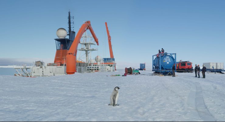Schneelandschaft, ein Pinguien steht neben mechanischen Geräten