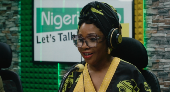 Filmstill aus STOFF. Eine Frau trägt Kopfhörer und spricht in ein Mikrofon.