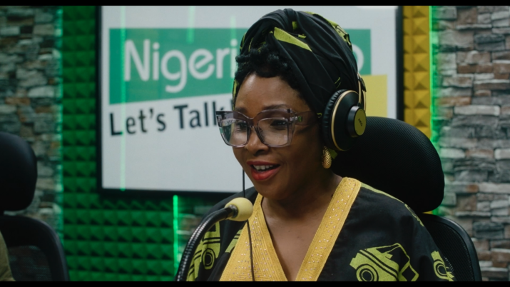 Filmstill aus STOFF. Eine Frau trägt Kopfhörer und spricht in ein Mikrofon.