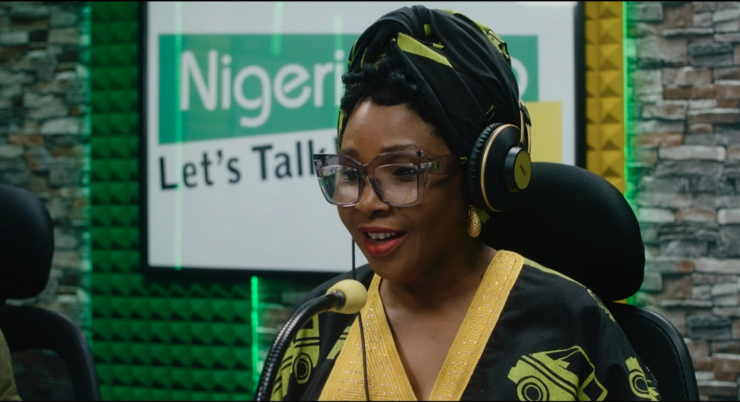 Filmstill aus STOFF. Eine Frau trägt Kopfhörer und spricht in ein Mikrofon.