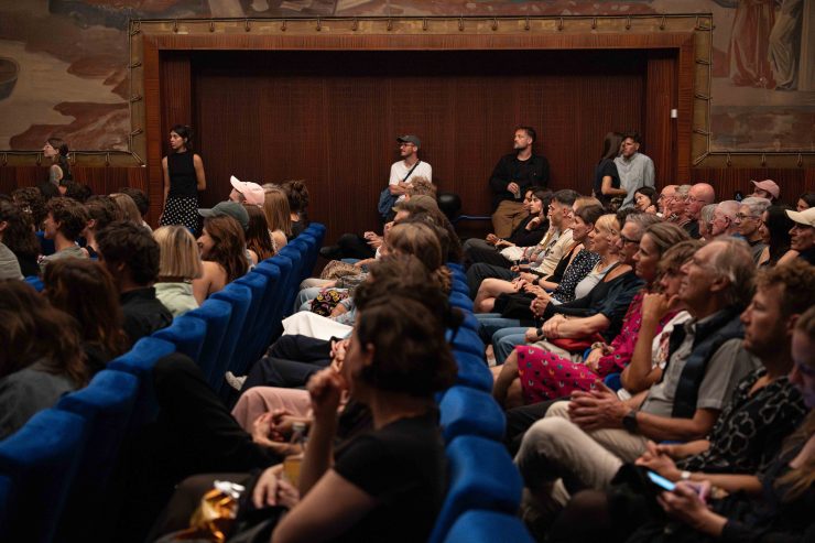 Seitenansicht Stadtkinosaal, viele Gäste auf den blauen Sesseln
