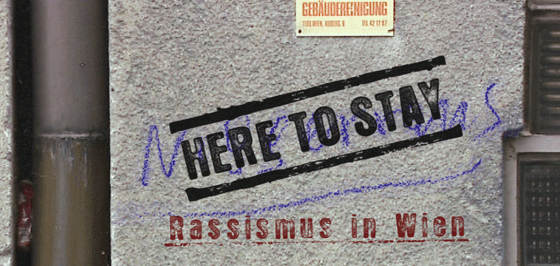 Der Titel "Here To Stay" ist auf einer Hauswand zu sehen.