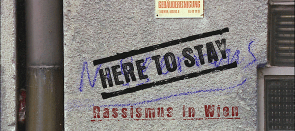 Der Titel "Here To Stay" ist auf einer Hauswand zu sehen.