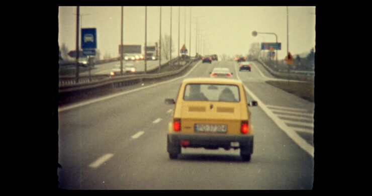 Kleiner gelber Kleinwagen fährt auf einer mehrspurigen Autobahn mit mehreren Fahrzeugen im Hintergrund
