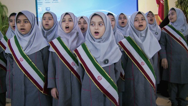 Gruppe von Mädchen in Schuluniformen mit weißen Kopftüchern und diagonalen Schärpen in den Farben Grün, Weiß und Rot.