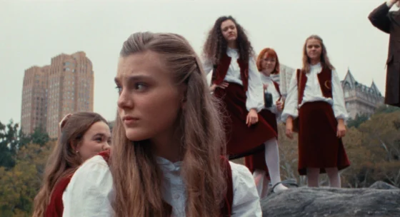 Gruppe von Mädchen in Schuluniformen steht im Freien vor einer Stadtlandschaft mit hohen Gebäuden