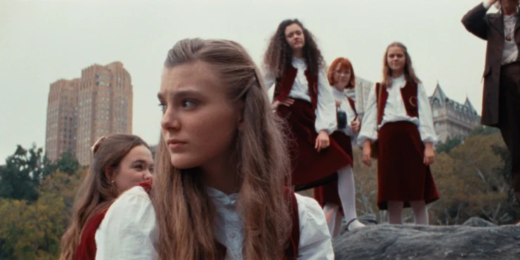 Gruppe von Mädchen in Schuluniformen steht im Freien vor einer Stadtlandschaft mit hohen Gebäuden