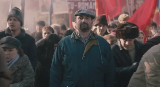Menschenmenge bei einer Demonstration mit roten Fahnen im Hintergrund