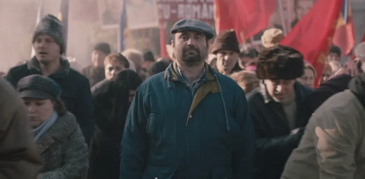 Menschenmenge bei einer Demonstration mit roten Fahnen im Hintergrund