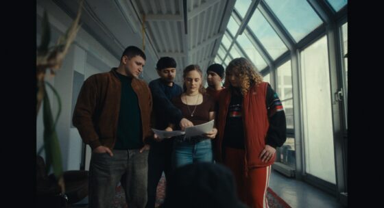 Fünf Jugendliche stehen im Halbreis und blicken gemeinsam auf einen Zettel.