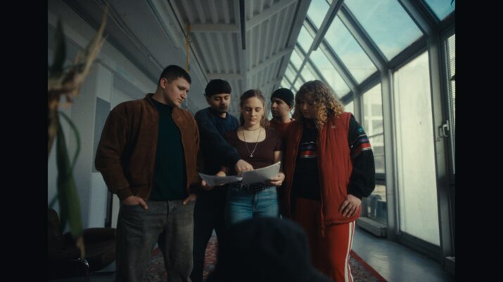 Fünf Jugendliche stehen im Halbreis und blicken gemeinsam auf einen Zettel.