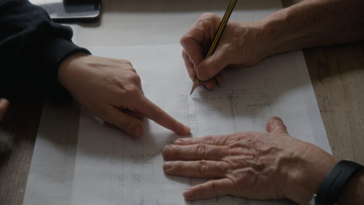Zwei Hände zeigen und zeichnen auf einem Blatt Papier mit Skizzen und Notizen