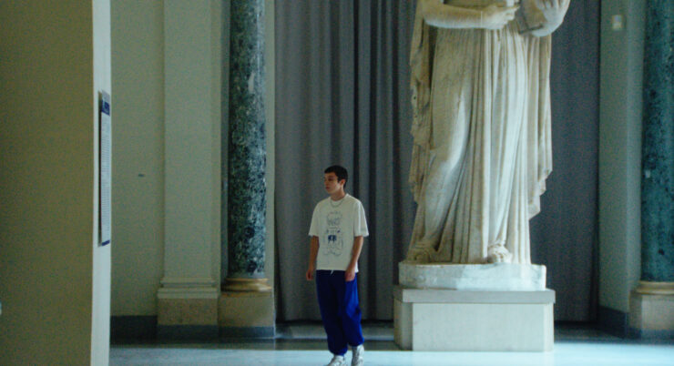 Ein junger Mann steht neben einer großen Statue.
