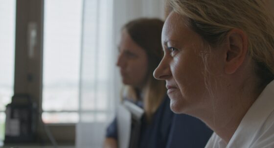 Zwei Frauen blicken nach links, dahinter ist ein Fenster zu sehen.