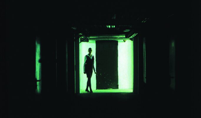 Person steht in einem dunklen Flur vor einem hell erleuchteten Ausgang